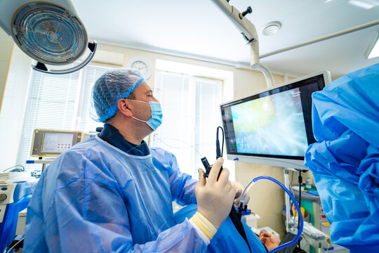 Doctor performing endoscopy with medical monitor. Doctor in protective uniform using endoscopic medical equipment with a monitor in hospital.