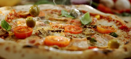 Delicious green olives falling in slow motion onto a freshly baked steaming pizza with tomatoes, mozzarella, bacon, and basil leaves in a close-up view perfect for food commercials - Powered by Adobe