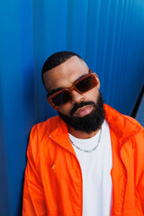 Fototapeta premium Portrait of bearded black man in sunglasses and windbreaker jacket posing in port 