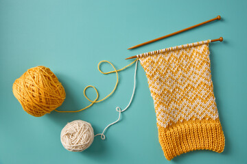 Knitting project in progress with yellow and white yarn, interweaving threads of different colors.