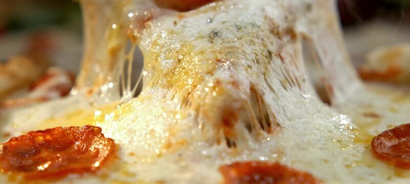 Vertical video of close-up of a hot slice of pepperoni pizza being lifted, showing the delicious melted mozzarella cheese stretching in thin, gooey strings, perfect for advertising and foodie content