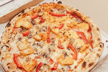 Delicious pizza topped with chicken, mushrooms, and red peppers placed in a cardboard box. Ideal for sharing during gatherings or enjoying quiet meals at home.