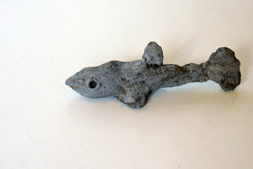 A grey clay figurine in a shape of a shark carved by a child