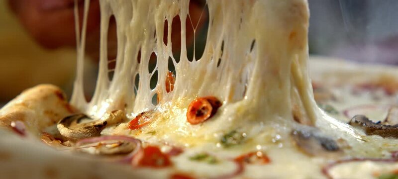 Vertical video of steaming hot pizza slice being lifted from the whole pizza with melted mozzarella cheese stretching in slow motion. delicious vegetarian meal with mushrooms, onions, and tomatoes