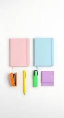 Overhead shot of pink and blue notebooks, orange stapler, yellow pen, green highlighter, and purple sticky notes isolated on white background, creating a minimalist and organized workspace for writing