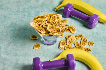 A lively scene of banana chips served in a glass bowl, complemented by fresh bananas and purple...
