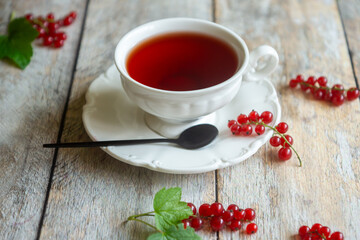 Red currant cake and a cup of aromatic tea in a porcelain cup on the table.