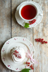 Red currant cake and a cup of aromatic tea in a porcelain cup on the table.
