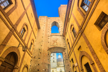 Obraz premium Photo of old stone gateway in front of cathedral showing medieval architecture, carved details, rustic facades and authentic Tuscan atmosphere in the historic center of Siena
