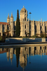 Obraz premium Portugal, Lisbon, Belem. Hieronymites Monastery - Mosteiro dos Jeronimos. Built in Gothic-Manueline style. Reflected on fountain water. One of Lisbon's most visited monuments. Late afternoon sunshine.