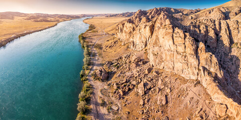 Aerial panoramic view of Ili River flowing through canyons and desert landscape in Kazakhstan at sunset