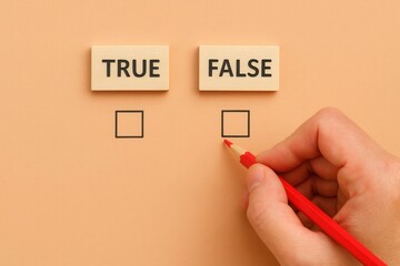 A hand with a red pencil approaches the check box next to the word "false," while "true" is displayed nearby, representing choices and contrasting concepts on a smooth, peach-colored background.
