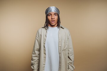 Young person with a surprised expression in casual attire against a neutral background