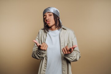 Young man posing confidently against a simple background in a casual outfit while making peace signs with his hands
