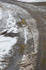 Snow-covered street with slush near urban area during winter season