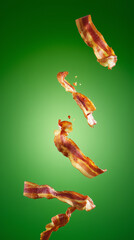 Crispy bacon strips falling against a vibrant green background.