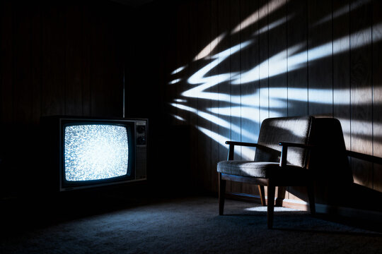 An old television glows with static in a dark room beside an empty armchair, creating a suspenseful and mysterious atmosphere with dramatic shadows.