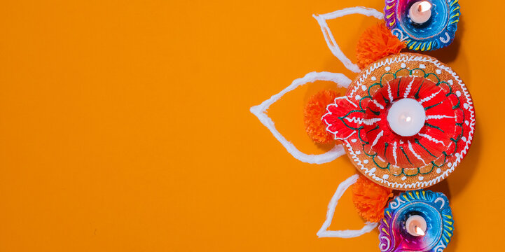 Colorful clay Diya lamps decorated using beads  and paint on yellow background isolated for Diwali copyspace - Powered by Adobe