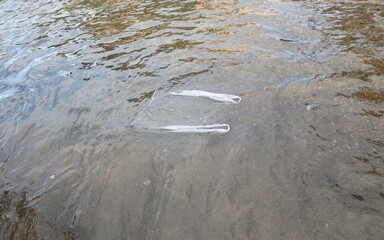Clear plastic bags floating on the flooded road. Maintain cleanliness.