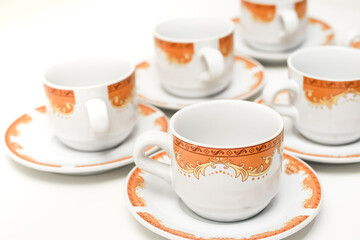 Elegant white ceramic tea cups with orange decorative patterns on a clean background