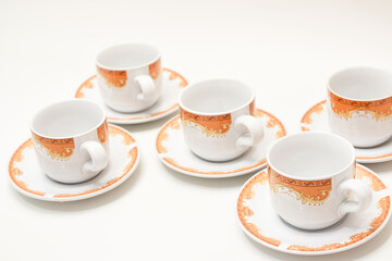 Elegant porcelain coffee cups with orange ornate design on a crisp white background