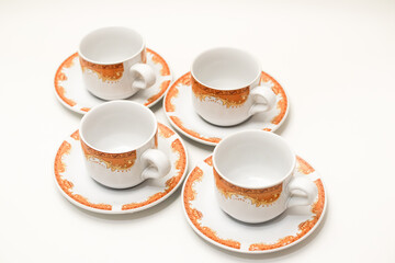 Elegant white and orange porcelain espresso cups and saucers, perfectly arranged on a clean white surface