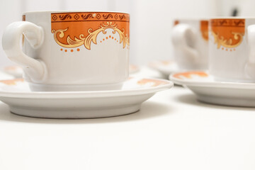 Elegant coffee cups with intricate gold and brown floral design on a bright background