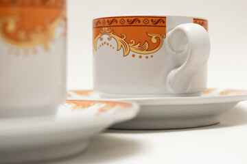 Elegant porcelain coffee cups with intricate golden and orange filigree design