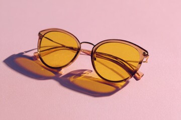 A pair of stylish sunglasses with yellow-tinted lenses rests on a minimalist white table, showcasing a bright and cheerful atmosphere with soft shadows and a pastel color palette.