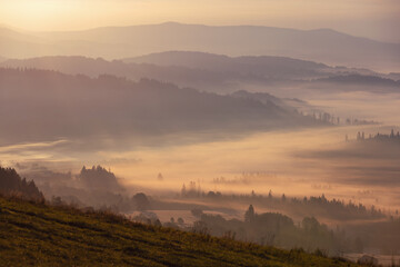 Jesienny widok na góry i spokojny krajobraz z mgłą i słońcem o świcie, Beskidy, Polska, tło lub fototapeta © anettastar