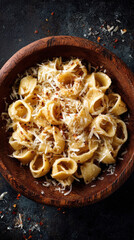 A delicious plate of pasta in a wooden bowl, ready to enjoy. The pasta is topped with cheese and spices, promising a rich and flavorful meal