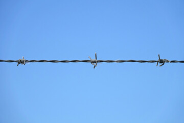 Simple line of barbed wire stretching across a blue background
