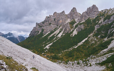 The mountain landscape of wild Friuli Dolomites, UNESCO Heritage Site. Nature reserves Dolomiti Friulane and Forra del Cellina. Impressive mountain range with Cima Brica. Female hiker in a trail.