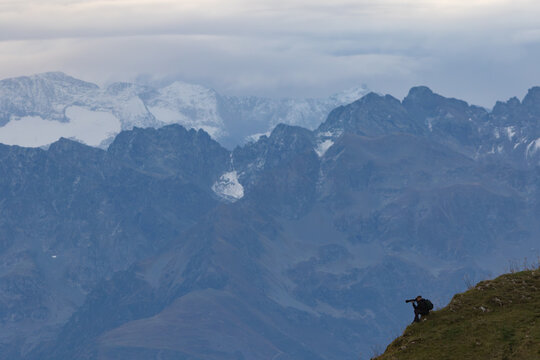 Fototapeta Photographe animalier avec téléobjectif dans un paysage matinal des Alpes françaises en Chartreuse avec massif de Belledonne et ciel nuageux