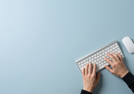 Overhead View of Hands Typing on Wireless Keyboard and Mouse on Clean Minimal Blue Desk Background