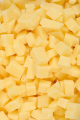A detailed close-up shot shows a horizontal pattern completely filled with yellow cheese cubes, creating a textured background
