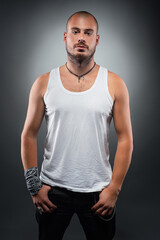 Fototapeta premium Confident Bald Man Posing in White Tank Top with Dramatic Lighting