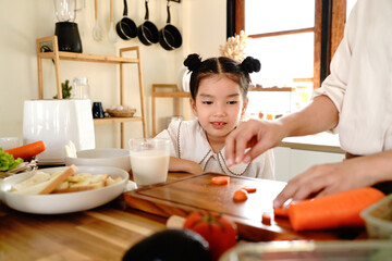 Mother and happy girl Make a salad in kitchen as a family with a young kid learning recipe at home. salad pastry, cut or mother helping or teaching daughter to bake for child development