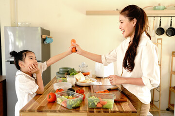 A mother and a child are preparing food together in cozy kitchen at home. The woman is teaching the child how to cook
