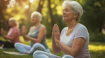 Senior women practicing yoga and meditating in a sunny park  