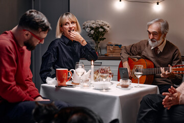 Family riends shares a cozy evening at a table with cheerful conversation, music, and good company....