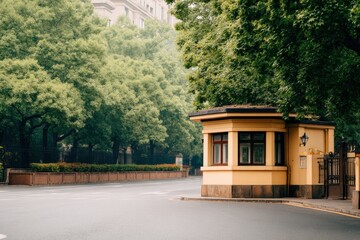 Serene urban scene of a quaint yellow guardhouse surrounded by lush greenery on a quiet street