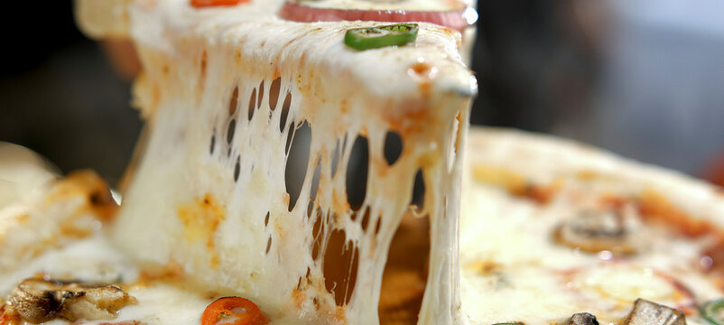 Hand lifting a pizza slice, showcasing the stretchy, gooey melted mozzarella cheese pull, highlighting the fresh and appetizing texture of the italian dish