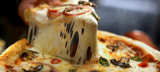 Person is carefully pulling a hot, steaming pizza slice with rich, melted mozzarella cheese stretching generously, emphasizing the delicious texture and fresh preparation