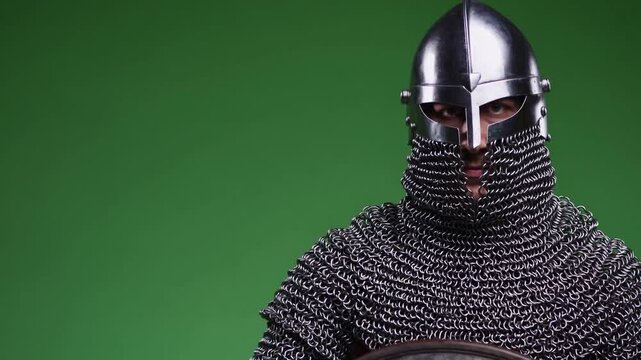 Medieval reenactor showcases chain mail armor and shield in studio setting
