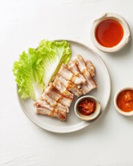 Samgyeopsal (삼겹살) : Grilled meat with sauces and lettuce on a plate.