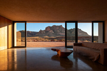 Interior living room with large sliding glass doors and desert mountain landscape view in the background