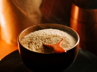 Couscous steaming in a wooden bowl with a wooden spoon resting inside