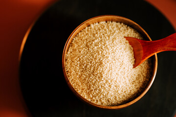 Couscous in a wooden bowl with a wooden spoon ready for cooking or meal preparation
