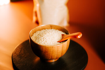Simple uncooked couscous displayed in a wooden bowl with a wooden scoop